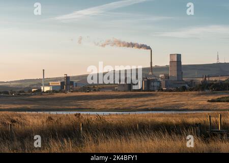 Travaux de fabrication de ciment de Dunbar vus à travers les prairies ouvertes et le lagon de carrière en début de matinée en plein soleil d'automne. Banque D'Images