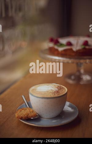 Tasse de café avec un motif de coeur dans une tasse sur une soucoupe sur un fond en bois dans un café. Banque D'Images