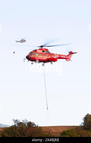 Un Airbus Red H215 remplit un seau d'eau alors qu'il combat le feu de forêt espagnol Estepona Banque D'Images