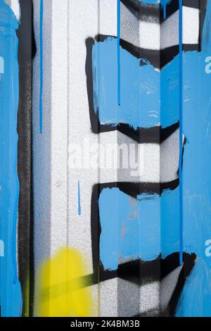 Lettre E blanche en majuscules peinte sur un mur en métal ondulé avec fond bleu. Banque D'Images