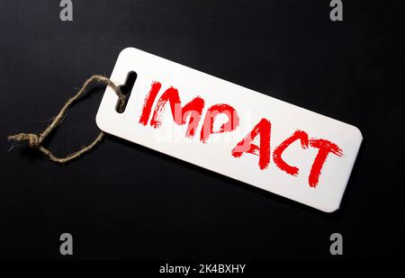 mot d'impact écrit sur fond gris avec des crayons et des trombones. Banque D'Images
