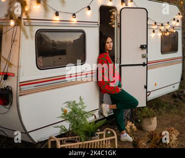 Une femme caucasienne en pull tricoté rouge surdimensionné voyage à motorhome en automne. Banque D'Images