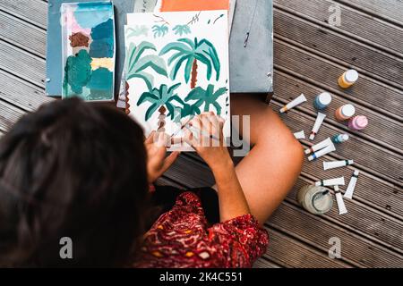 Jeune femme peintre peinture à côté de la palette et des tubes de peinture Banque D'Images