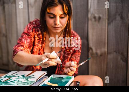 Jeune femme peintre avec un tube de peinture dans sa main préparant la peinture avant la peinture Banque D'Images