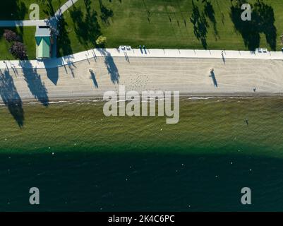Une vue aérienne de dessus d'un parc en bord de mer avec une plage paysagée, ensoleillé par jour ensoleillé. Banque D'Images
