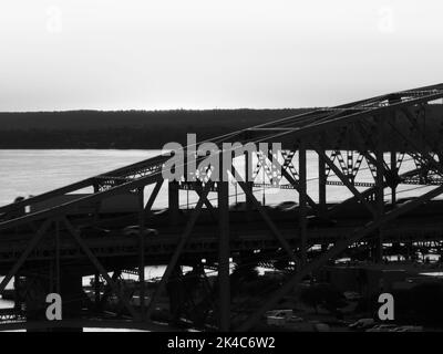 Une photo en noir et blanc d'un pont de treillis sur l'eau, comme la circulation, le mouvement flou, voyage à travers. Banque D'Images