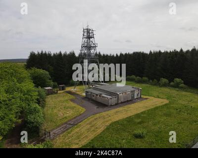 Vue d'un drone d'un derrick dans un champ vert avec une forêt autour sous ciel nuageux Banque D'Images