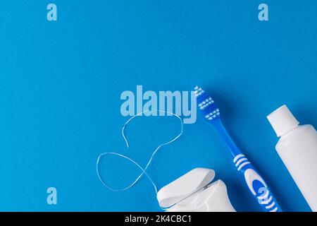 Image d'une brosse à dents, d'un dentifrice et d'une corde dentaire sur une surface bleue Banque D'Images