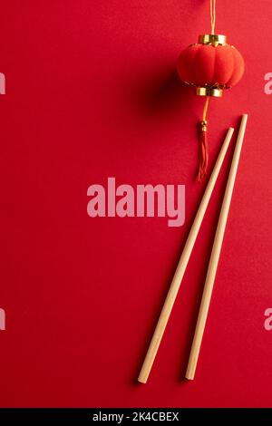 Composition de décorations et baguettes chinoises traditionnelles sur fond rouge Banque D'Images