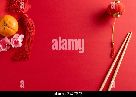 Composition de décorations et baguettes chinoises traditionnelles sur fond rouge Banque D'Images