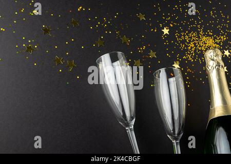 Composition de gros plan de champagne du nouvel an et confetti sur fond noir Banque D'Images