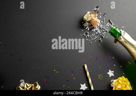 Composition de gros plan de champagne du nouvel an et confetti sur fond noir Banque D'Images