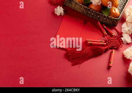 Composition de décorations chinoises traditionnelles et de fleurs sur fond rouge Banque D'Images