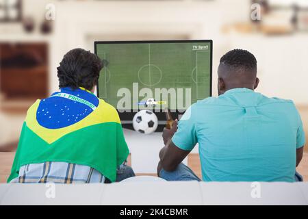 Divers amis regardant la télévision avec un match de football à l'écran Banque D'Images