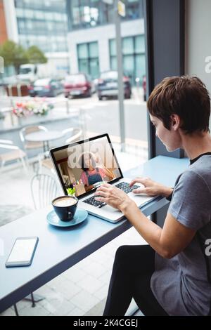 Femme d'affaires ayant une tasse de café tout en utilisant un ordinateur portable dans le bureau Banque D'Images