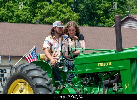 Eau Claire MI USA, 4 juillet 2022; Un sourire de famille lorsqu'ils conduisent le grand tracteur John deere lors d'une parade du 4th juillet Banque D'Images