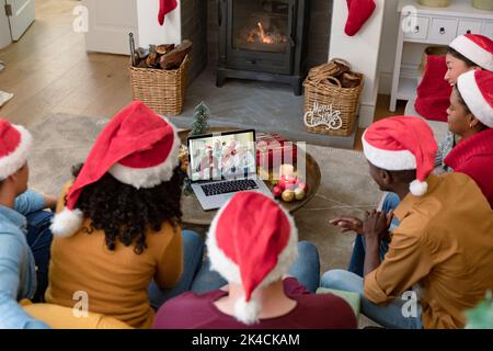 Amis biraciaux à santa chapeaux sur ordinateur portable de noël appel vidéo avec la famille. . noël, fête et technologie de communication. Banque D'Images