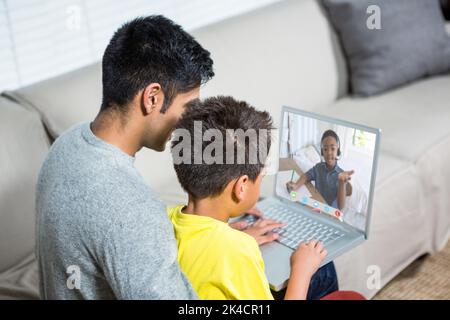 Père et fils utilisant un ordinateur portable sur le canapé dans la salle de séjour Banque D'Images