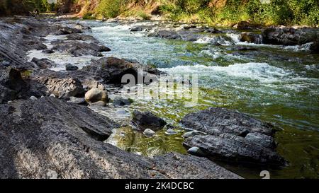 L'eau turbulent de la rivière se précipitant à travers les rochers et les rapides lors d'un jour d'automne brillant. Banque D'Images