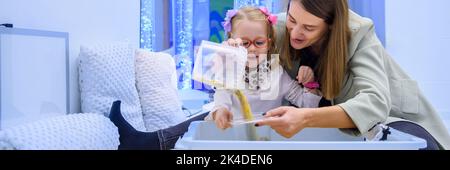 Enfant avec un handicap physique dans la chambre stimulante sensorielle, snoezelen. Enfant vivant avec une paralysie cérébrale interagissant avec son thérapeute pendant la thérapie Banque D'Images