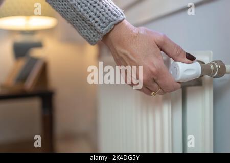 Femme ajustant la température sur radiateur de chauffage, concept de crise énergétique en Europe, augmentation des coûts dans les ménages privés pour la facture de gaz en raison de l'inflation et Banque D'Images