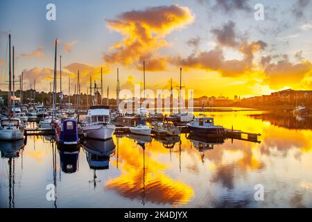 Preston Lancashire. Météo au Royaume-Uni ; 2 octobre 2022. Le soleil sec et lumineux commence la journée, tandis que l'aube se brise au-dessus des bateaux amarrés à Preston Dock. Les nuages de diffusion de Rayleigh où les longueurs d'onde plus longues de la lumière, comme l'orange, sont les moins dispersées par les molécules dans l'atmosphère et la lumière du soleil doit traverser une plus grande partie de l'atmosphère lorsque le Soleil est bas dans le ciel. Une journée en grande partie sèche à suivre avec beaucoup de soleil d'automne au-dessus de la marina de yacht à navigation Way, Riversway Docklands Preston. Crédit : MediaWorldImages/AlamyLiveNews Banque D'Images