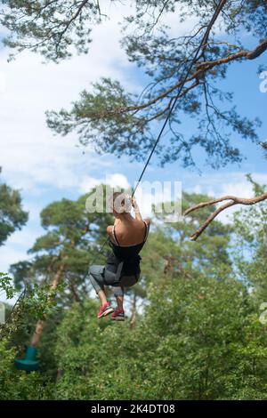 Adolescente sur une ligne de fermeture à glissière dans un centre d'escalade des arbres Banque D'Images