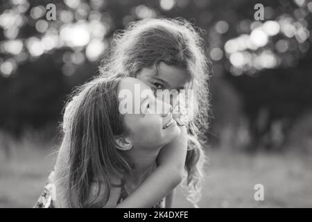 Portrait noir et blanc de deux petites filles rire heureux et s'étreindre au parc d'été. Banque D'Images