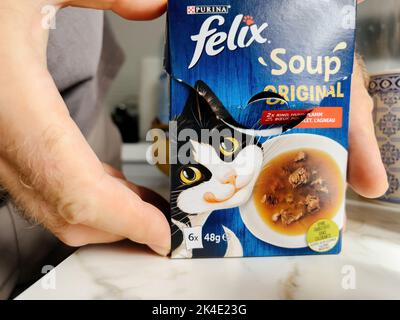 Paris, France - 13 septembre 2022: POV main mâle tenant carton paquet avec des pochettes avec Felix Soup avec boeuf - cuisine moderne fond se préparant à nourrir l'animal de chat Banque D'Images