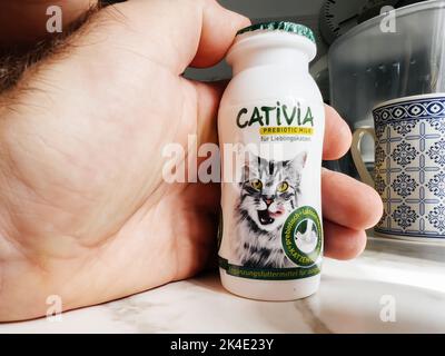 Paris, France - 13 septembre 2022: POV main mâle tenant une bouteille en plastique métallique avec lait probiotique Cativia - cuisine moderne fond se préparant à nourrir l'animal de chat Banque D'Images