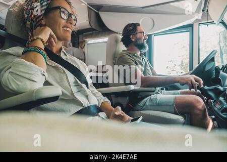 Vue latérale d'un couple de voyageurs heureux à l'intérieur d'un camping-car en voiture de camping et en train de profiter de vacances sur route ou d'un style de vie sans fin. Personnes et trans Banque D'Images