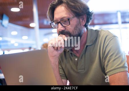 Portrait d'un homme travaillant sur un ordinateur portable dans un autre bureau de magasin. Les gens et la technologie moderne travail informatique activité de loisirs. Mûrir avec la barbe et le verre Banque D'Images