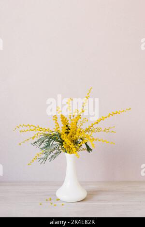 Bouquet de fleurs mimosa jaunes dans un vase en céramique blanc. Le concept de 8 mars, Pâques, bonne journée des femmes Banque D'Images