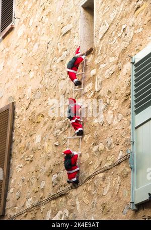 Trois Santa Claus grimpent l'échelle de corde sur une façade Banque D'Images