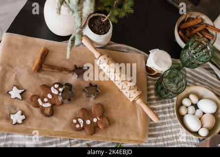 Petits gâteaux de Noël au gingembre faits maison décorés de glaçage se trouvent sur la table dans un style rustique Banque D'Images