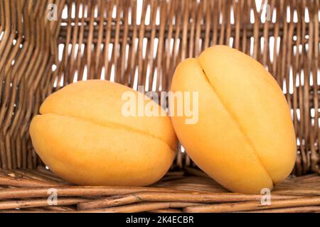 Deux abricots d'ananas juteux dans un panier de brindilles, gros plan. Banque D'Images