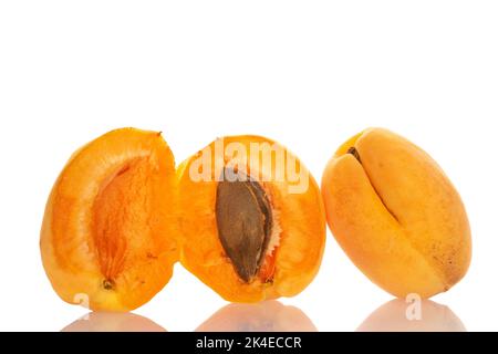 Une moitié entière et deux moitiés d'abricot ananas avec une graine, macro, isolée sur blanc. Banque D'Images