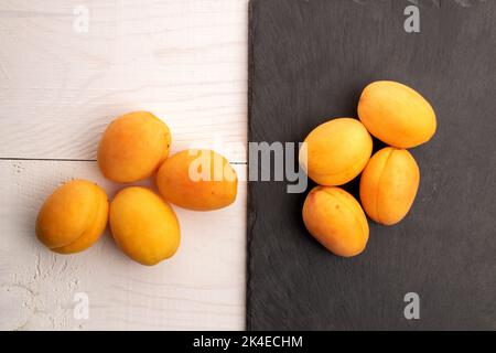 Plusieurs abricots mûrs d'ananas jaune, gros plan, sur un tableau d'ardoise et une table en bois blanc, vue du dessus. Banque D'Images