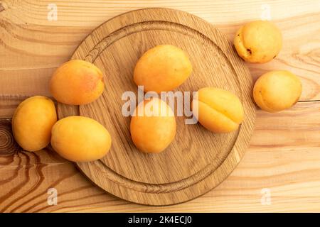 Plusieurs abricots d'ananas mûrs jaunes sur un plateau en bois, gros plan, sur une table en bois, vue de dessus. Banque D'Images