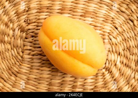 Un abricot jaune ananas, macro, sur un tapis de paille, vue de dessus. Banque D'Images