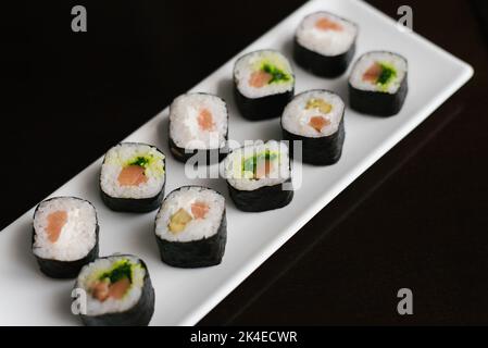Les petits pains avec salade de saumon et de chuka sont sur une assiette rectangulaire blanche Banque D'Images