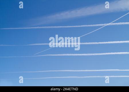 Six sentiers de condensation, contrails ou pistes de vapeur dans un ciel bleu, cinq parallèles et horizontaux et un qui les traverse Banque D'Images