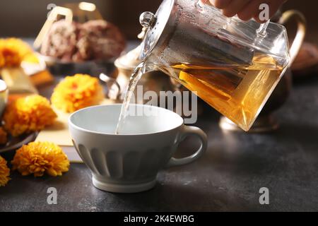 Verser le thé chaud de la casserole dans la tasse sur la table dans le café Banque D'Images