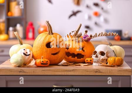 Citrouilles d'Halloween avec crâne humain et feuilles mortes sur le comptoir de la cuisine Banque D'Images