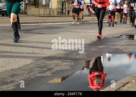 Silesia Marathon 2022, Katowice, Silésie, Pologne. 02 octobre 2022. Marathon de Silesia 2022. Les jambes des coureurs de marathon et la réflexion dans une flaque de bord de route Banque D'Images