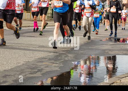 Silesia Marathon 2022, Katowice, Silésie, Pologne. 02 octobre 2022. Marathon de Silesia 2022. Les jambes des coureurs de marathon et la réflexion dans une flaque de bord de route Banque D'Images