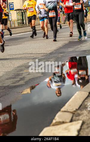 Silesia Marathon 2022, Katowice, Silésie, Pologne. 02 octobre 2022. Marathon de Silesia 2022. Les jambes des coureurs de marathon et la réflexion dans une flaque de bord de route Banque D'Images