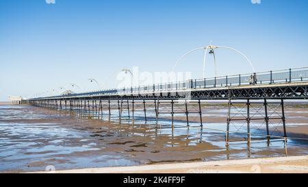 Southport Pier se reflétant dans les bassins d'eau laissés à marée haute en octobre 2022 sur la côte de Sefton. Banque D'Images