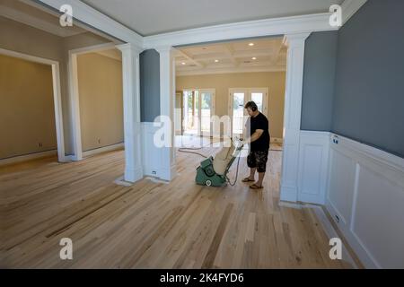 Le processus de meulage d'un parquet en bois avec l'utilisation d'une ponceuse de plancher dans une maison nouvellement construite, qui suit Banque D'Images