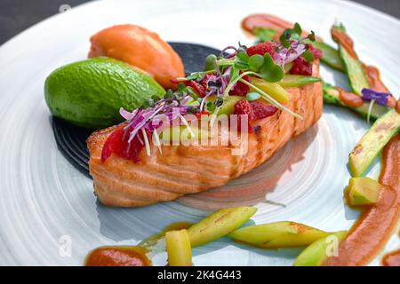 Filet de saumon aux tomates confites et asperges vertes aux spaghetti noirs, sauce pesto et sorbet carottes et fruits de la passion Banque D'Images